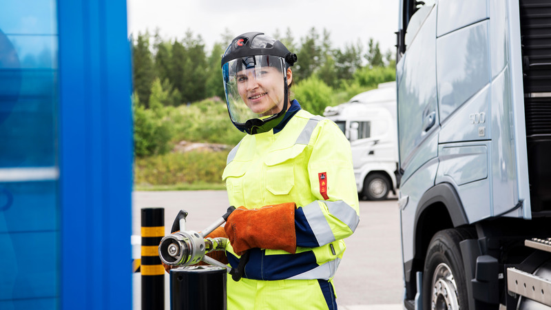 Naispuoleinen rekka-auton kuljettaja tankkaamassa rekkaa Gasumin tankkausasemalla. 