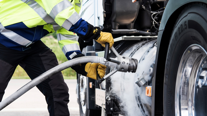 Ihminen lähikuvassa tankkaamassa kuorma-autoa nesteytetyllä kaasulla. 